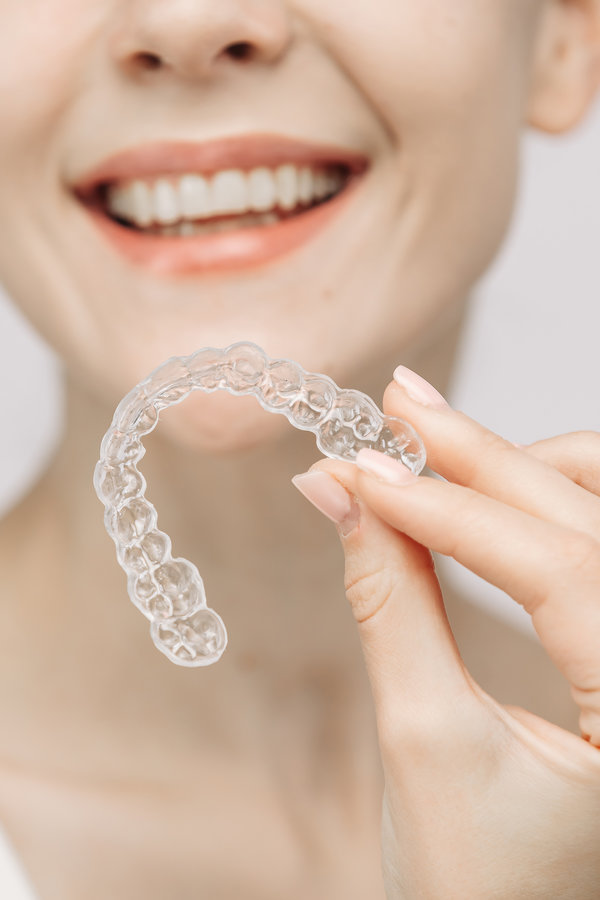 A woman uses an orthodontic silicone trainer for teeth correction. This mobile device highlights modern dental care methods and whitening systems, promoting a healthy and radiant smile.