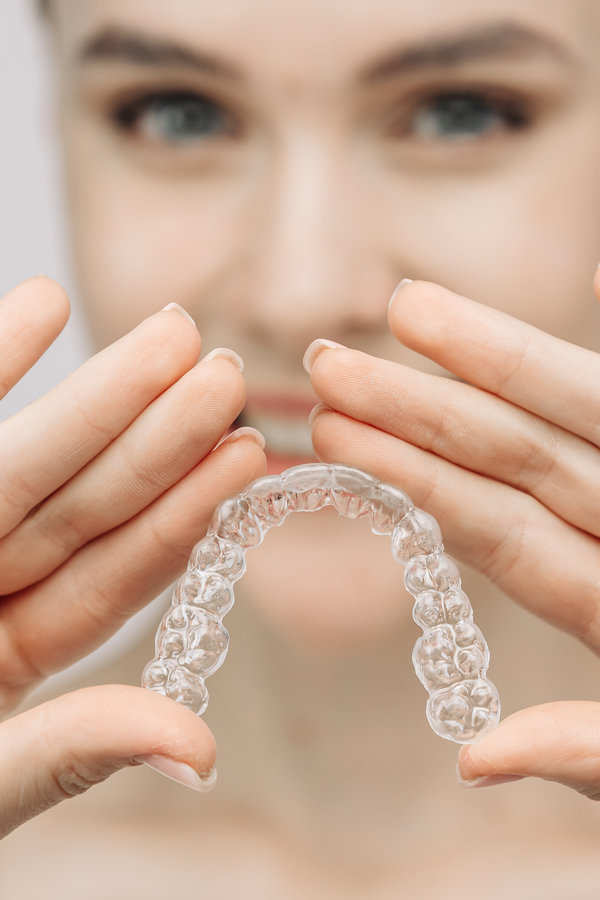 A woman uses an orthodontic silicone trainer for teeth correction. This mobile device highlights modern dental care methods and whitening systems, promoting a healthy and radiant smile.