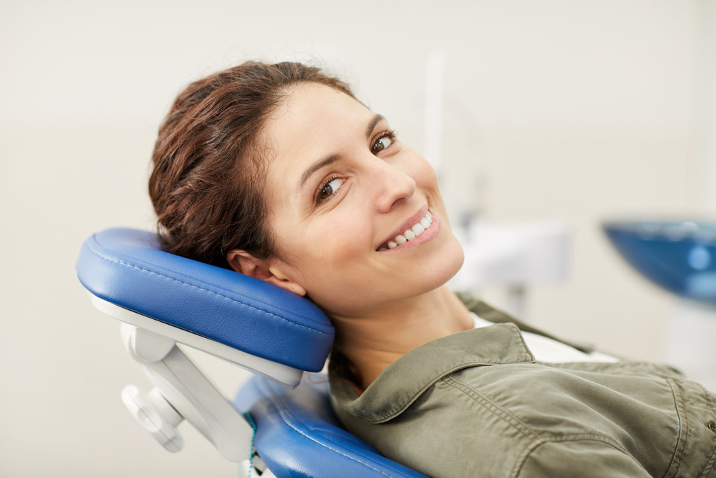 Woman at Dentists Consultation Portrait of smiling young woman lying in dental chair and looking at camera, copy space
