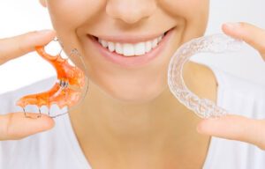 hands holding retainer for teeth and tooth tray