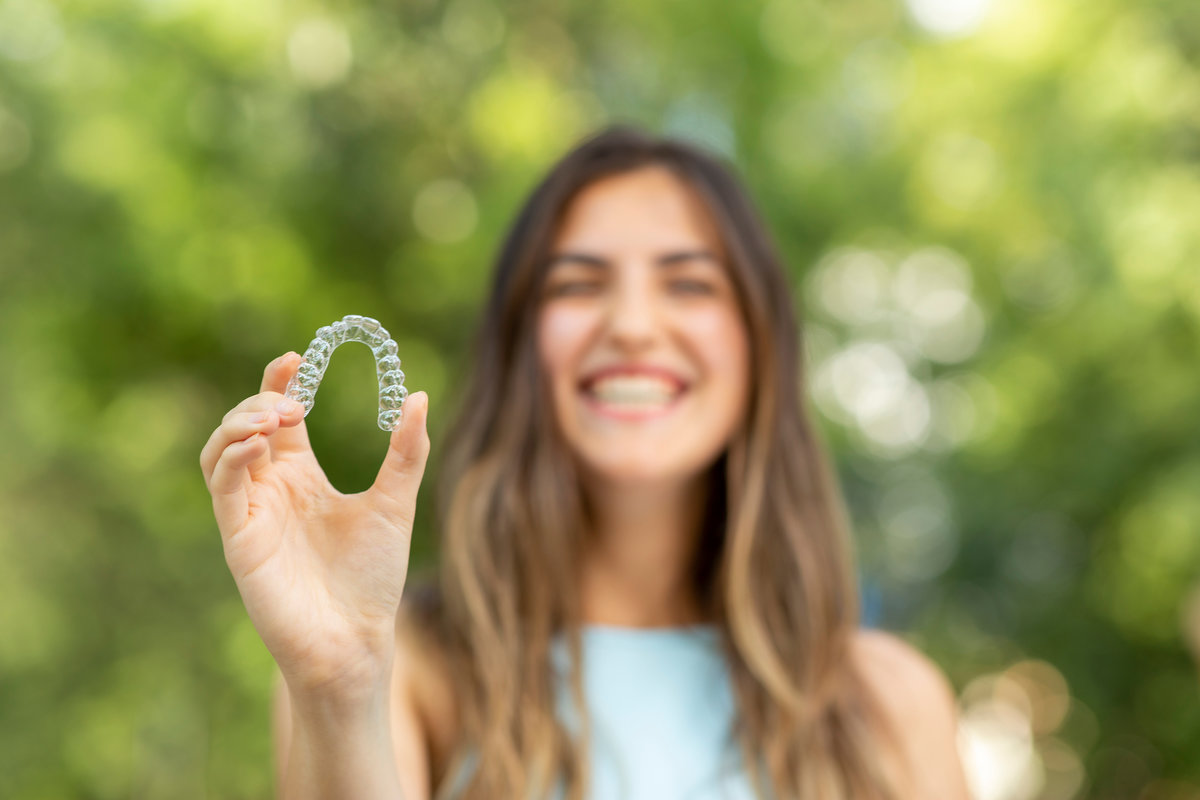 Beautiful smiling Turkish woman is holding an invisalign bracer