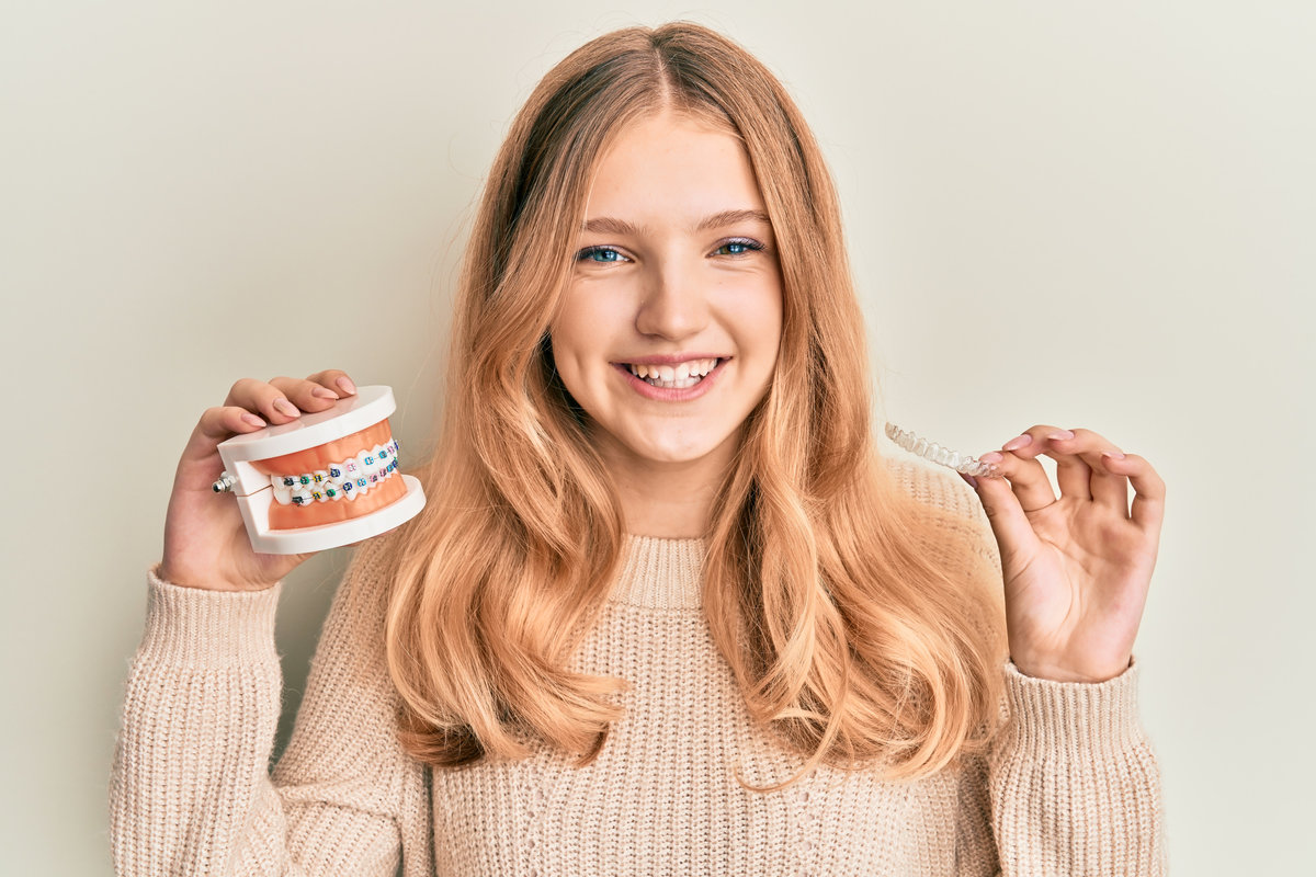 Beautiful young caucasian girl holding invisible aligner orthodontic and braces smiling with a happy and cool smile on face. showing teeth.
