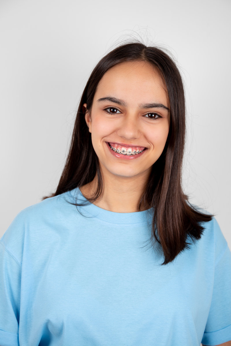 Portrait of a cute and happy teen girl with braces smiling. Isolated on white
