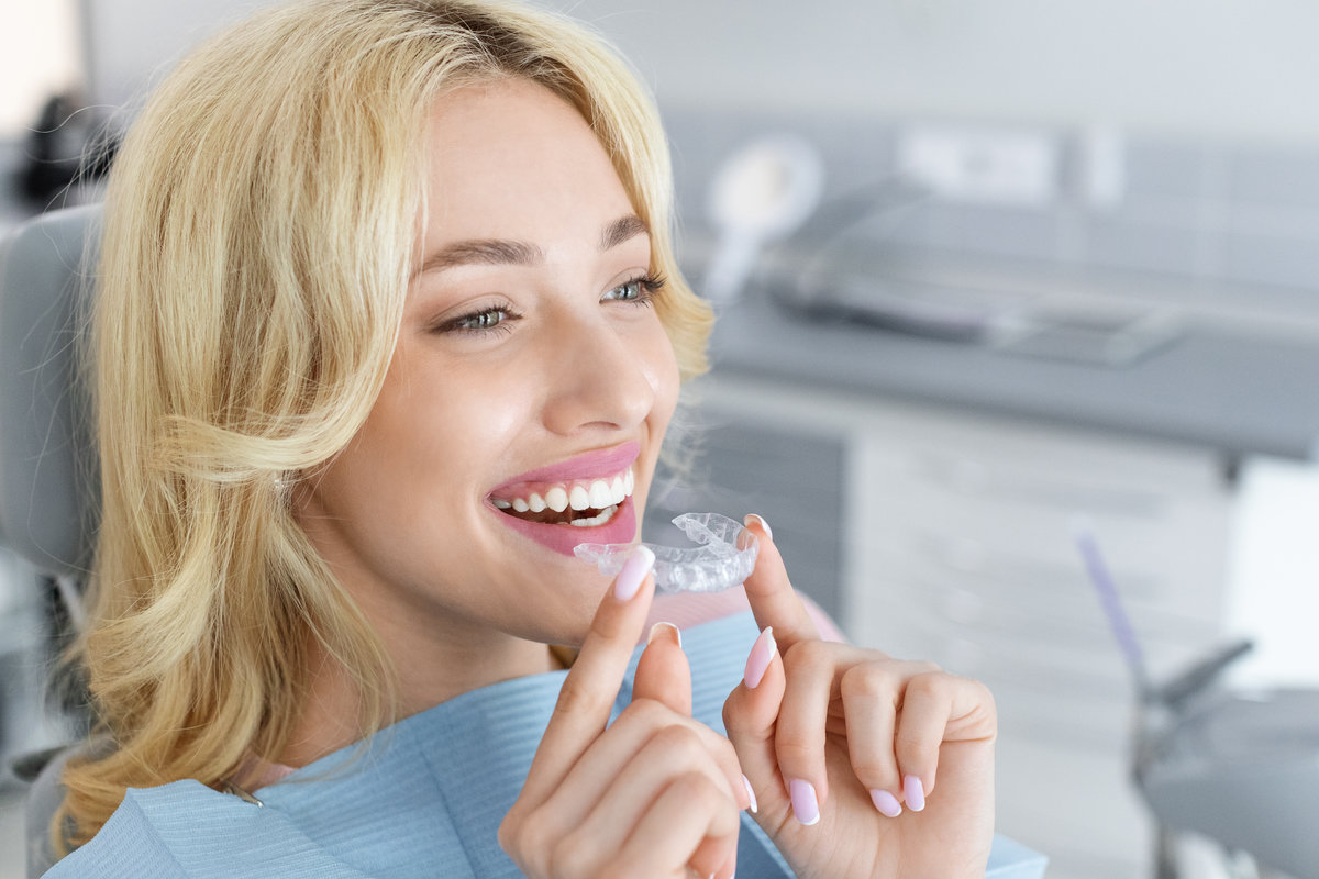 Young attractive woman holding invisible braces or trainer Airways and Orthodontics