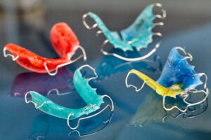 Colorful dental braces or retainers for teeth on blue glass background, closeup